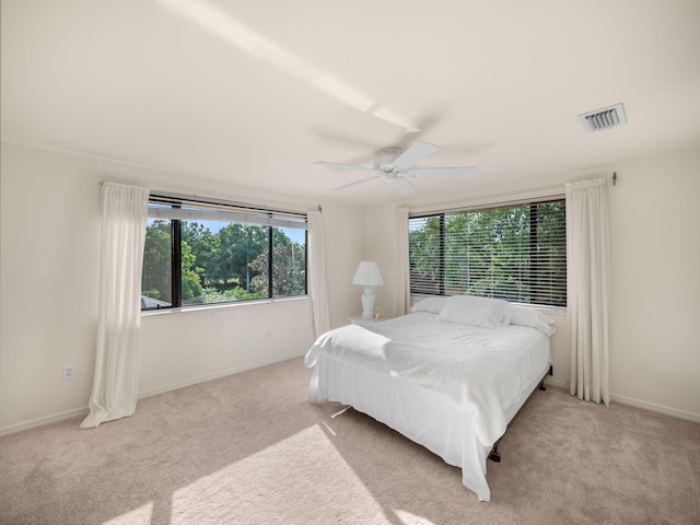 carpeted bedroom featuring multiple windows, a ceiling fan, visible vents, and baseboards