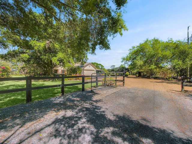 view of road featuring a rural view, a gated entry, driveway, and a gate