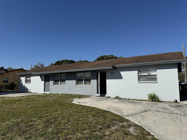 ranch-style home featuring stucco siding, brick siding, and a front lawn