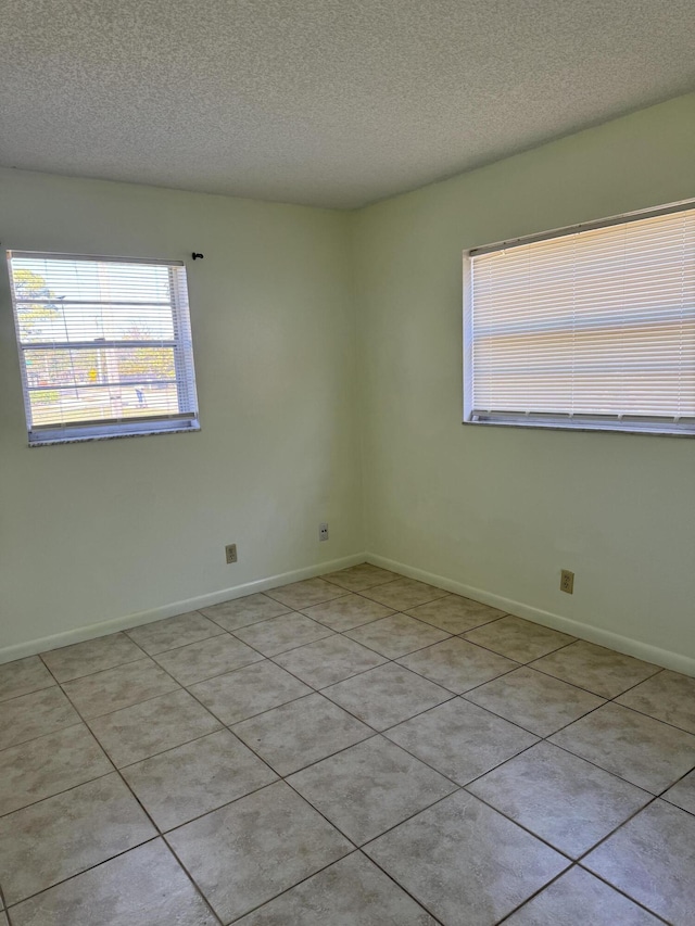 empty room featuring a textured ceiling and baseboards