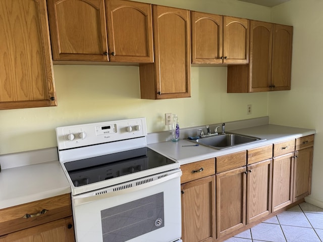 kitchen featuring white electric range, brown cabinets, light countertops, and a sink