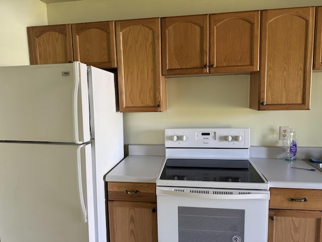 kitchen with white appliances, brown cabinetry, and light countertops