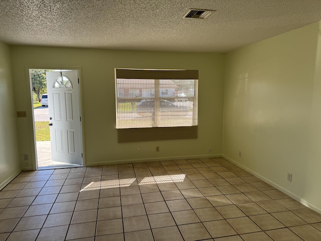 entrance foyer featuring light tile patterned floors, baseboards, visible vents, and a textured ceiling