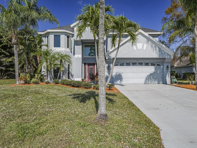 view of front of house featuring a front lawn, a garage, driveway, and stucco siding