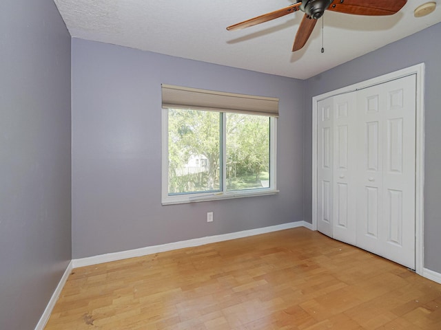 unfurnished bedroom featuring a closet, baseboards, light wood-style floors, and a ceiling fan