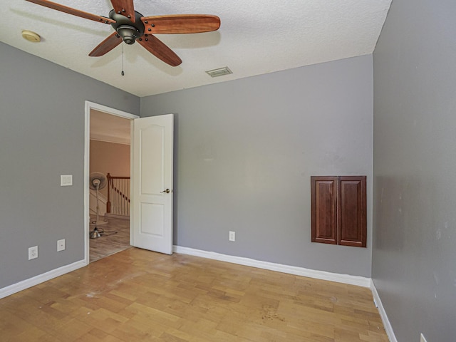 spare room featuring light wood finished floors, baseboards, and ceiling fan