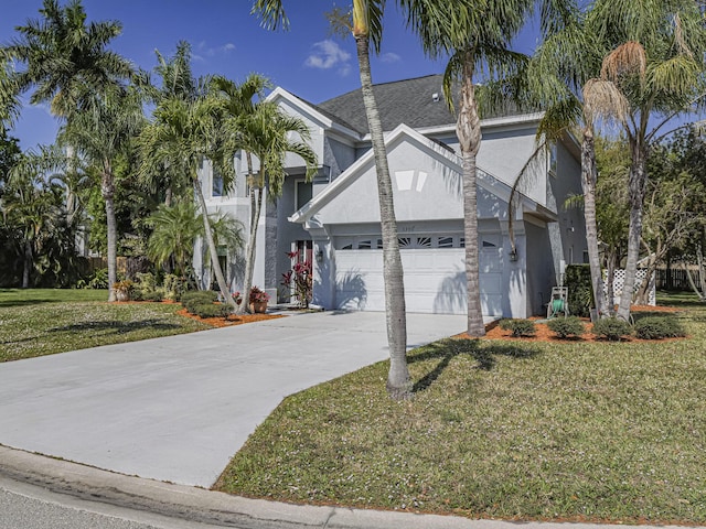 view of front of house with stucco siding, an attached garage, concrete driveway, and a front lawn