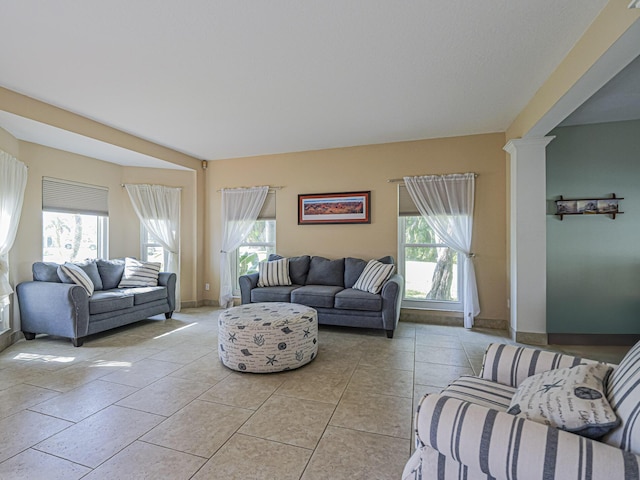 living area featuring light tile patterned floors, baseboards, and ornate columns