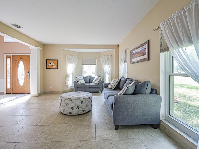 living area featuring light tile patterned flooring, visible vents, and baseboards