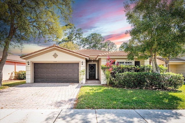 view of front of property featuring a tiled roof, decorative driveway, an attached garage, and stucco siding