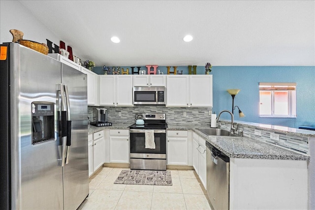 kitchen featuring a sink, stainless steel appliances, a peninsula, and white cabinetry