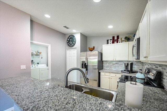 kitchen with tasteful backsplash, visible vents, separate washer and dryer, stainless steel appliances, and a sink