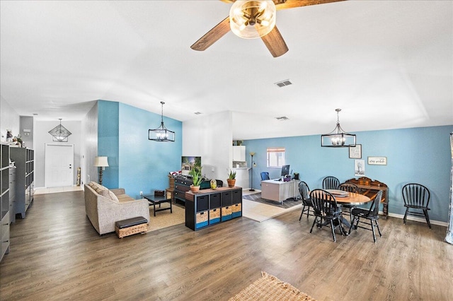 dining area with ceiling fan with notable chandelier, wood finished floors, visible vents, and baseboards