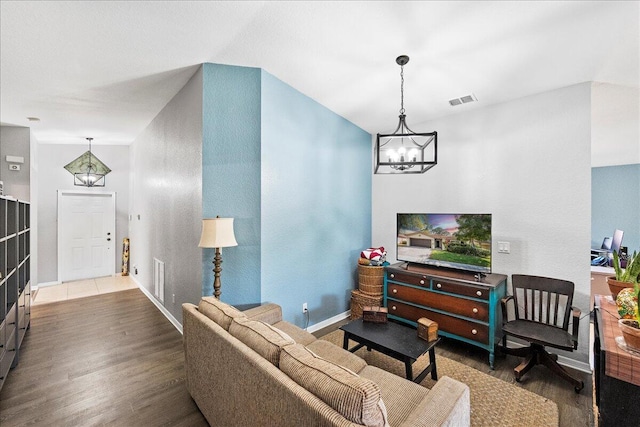 living room with visible vents, baseboards, an inviting chandelier, and wood finished floors