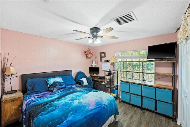 bedroom with visible vents, a textured ceiling, and wood finished floors