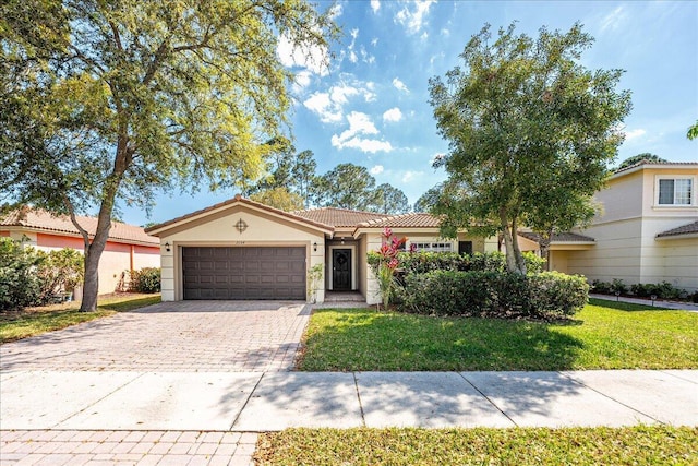 view of front of house featuring stucco siding, a front lawn, a garage, a tile roof, and decorative driveway