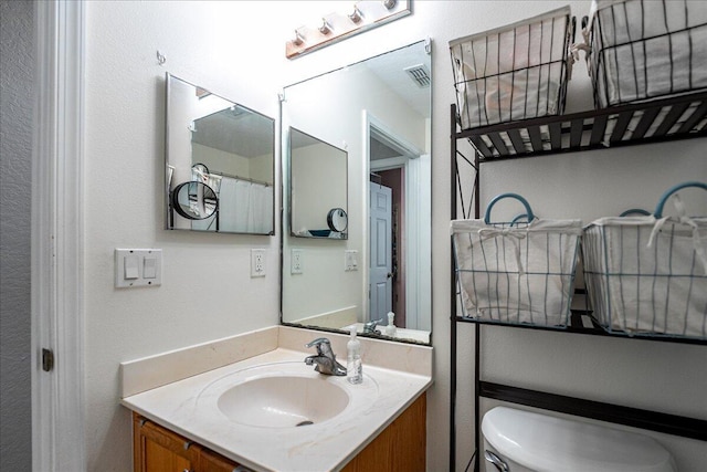 bathroom with visible vents, toilet, and vanity