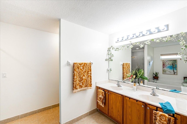 full bathroom featuring a textured ceiling, double vanity, tile patterned flooring, and a sink