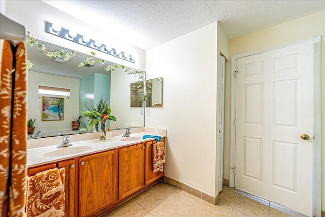 bathroom featuring a sink, a textured ceiling, double vanity, and tile patterned flooring