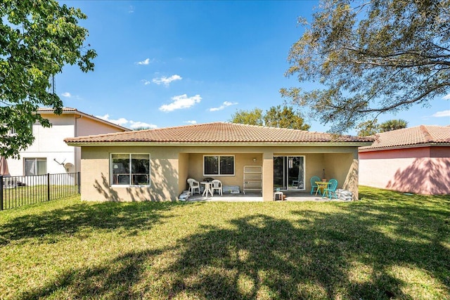 rear view of property with a tiled roof, a yard, fence, and stucco siding