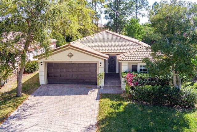 view of front of house featuring stucco siding, a front lawn, decorative driveway, an attached garage, and a tiled roof