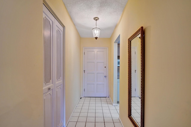 doorway to outside featuring baseboards, a textured ceiling, and light tile patterned flooring