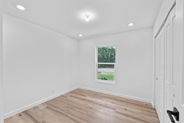 unfurnished bedroom featuring light wood finished floors, a closet, recessed lighting, and baseboards