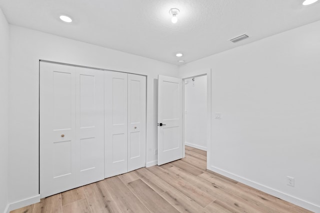 unfurnished bedroom with baseboards, visible vents, light wood-style flooring, recessed lighting, and a closet