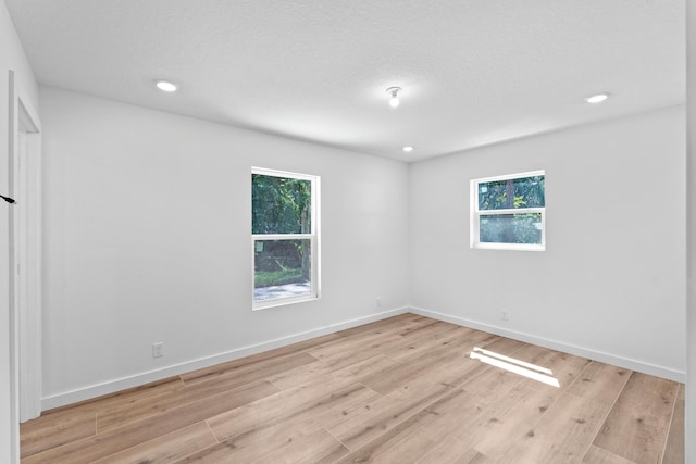 unfurnished room featuring recessed lighting, baseboards, and light wood-type flooring