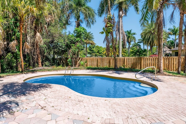 view of swimming pool featuring a patio and fence
