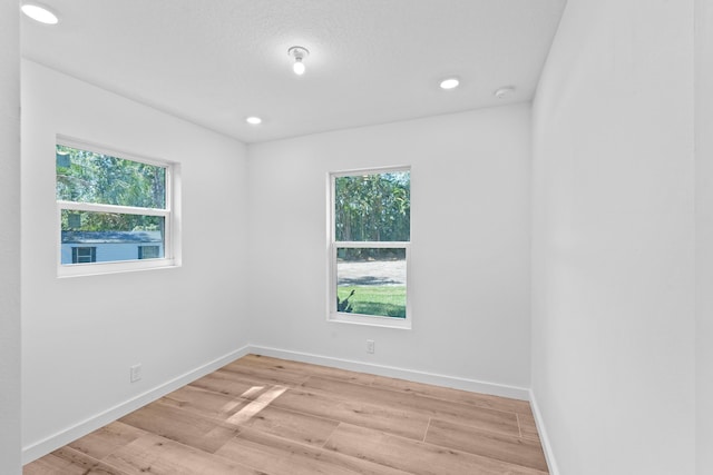 spare room featuring recessed lighting, light wood-style flooring, and baseboards