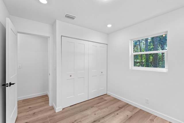 unfurnished bedroom with visible vents, baseboards, a closet, and light wood finished floors