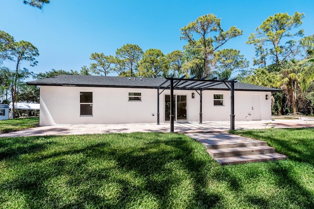 rear view of house featuring stucco siding, a lawn, and a patio