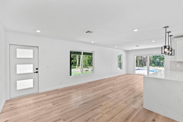 unfurnished living room with recessed lighting, light wood-type flooring, and baseboards