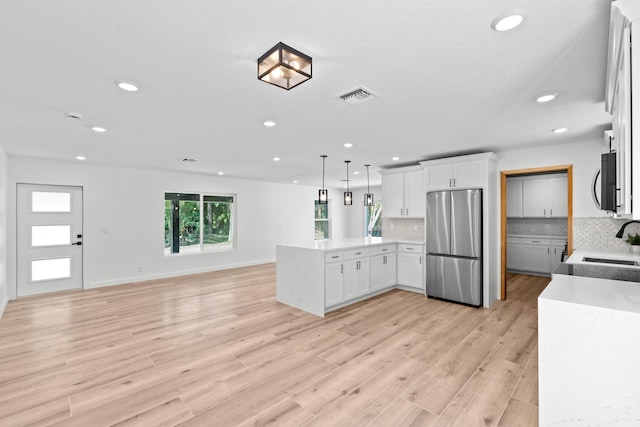 kitchen with visible vents, a peninsula, appliances with stainless steel finishes, open floor plan, and backsplash