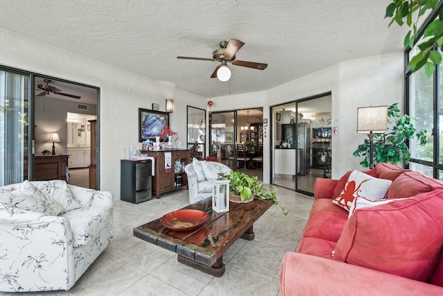 tiled living area featuring a ceiling fan, a textured wall, and a textured ceiling