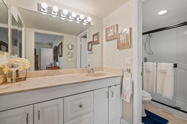 bathroom featuring toilet, a stall shower, vanity, and tile patterned flooring