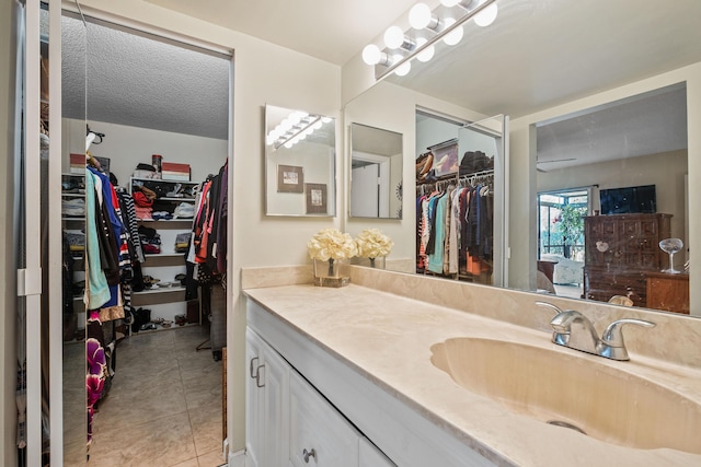 bathroom with tile patterned floors, a walk in closet, and vanity