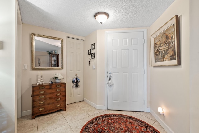 foyer with light tile patterned flooring, a textured ceiling, and baseboards