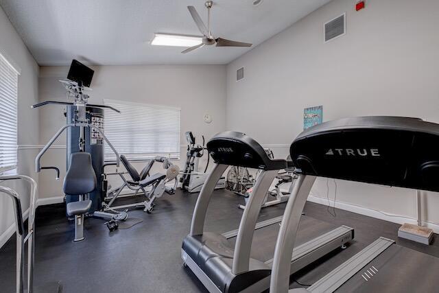 workout area with visible vents, baseboards, and ceiling fan