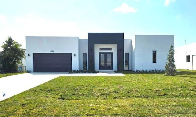 modern home featuring a front yard, stucco siding, concrete driveway, french doors, and a garage