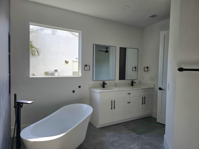 bathroom featuring double vanity, a soaking tub, visible vents, and a sink