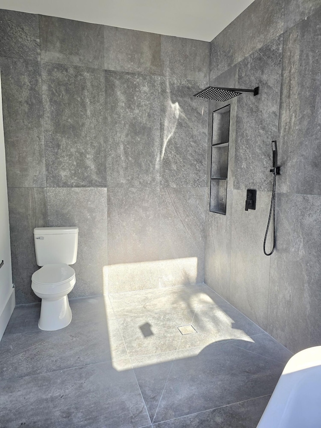 full bathroom featuring a tile shower, toilet, and tile walls