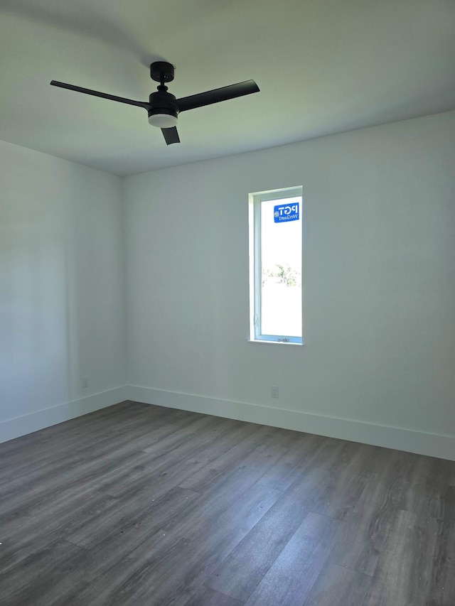 unfurnished room with a ceiling fan, dark wood-type flooring, and baseboards