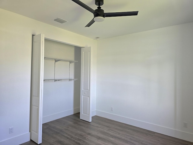 unfurnished bedroom featuring visible vents, baseboards, a closet, and dark wood finished floors