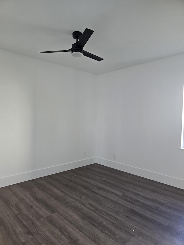 empty room featuring a ceiling fan, dark wood-style floors, and baseboards