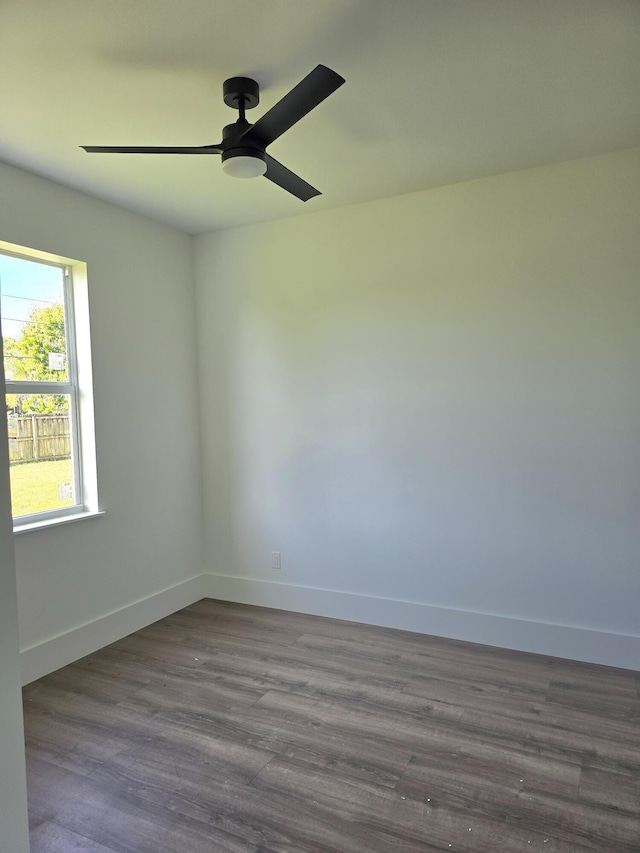 spare room featuring dark wood finished floors, a ceiling fan, and baseboards