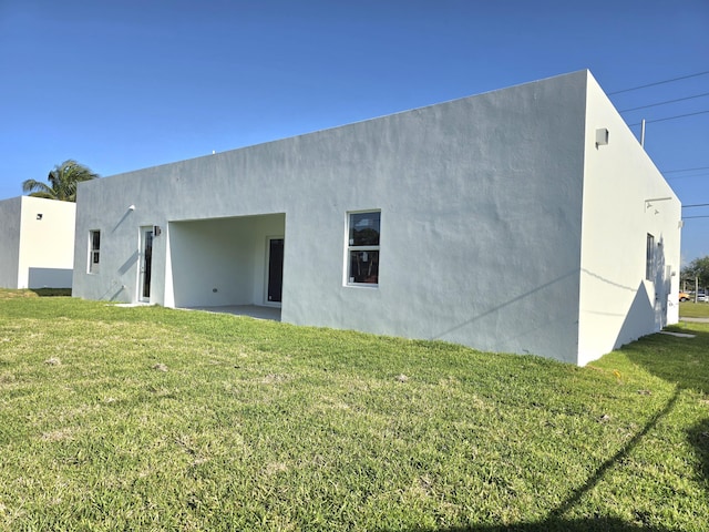 rear view of property with a lawn and stucco siding