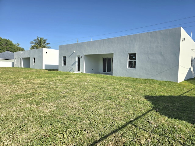 rear view of property with a yard and stucco siding