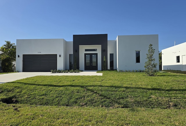 modern home featuring a front yard, stucco siding, french doors, driveway, and an attached garage